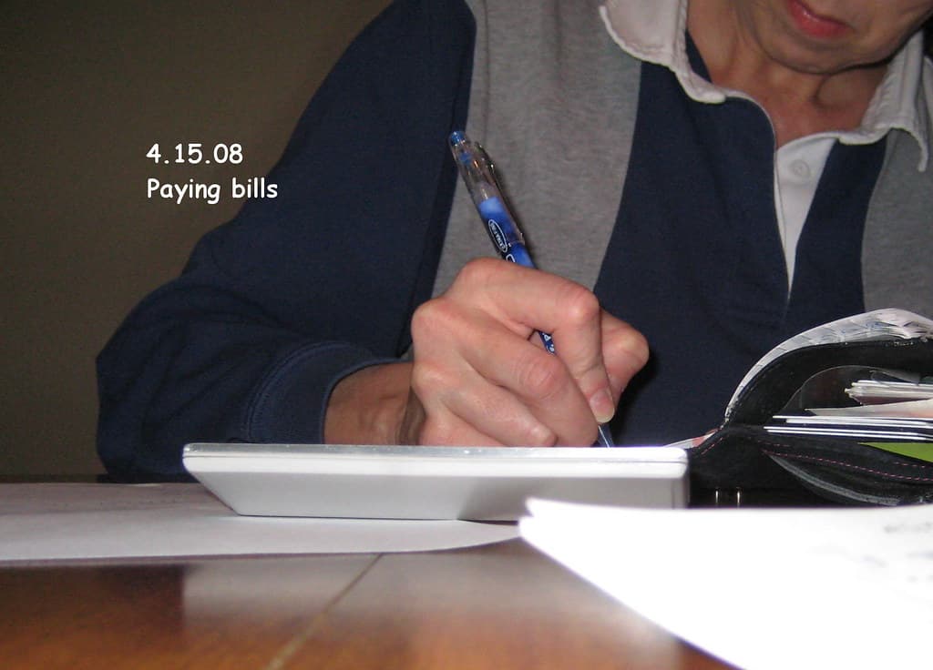 Paying bills and managing money at a desk — How to Pay Off $10,000 Debt in 12 Months on Any Salary